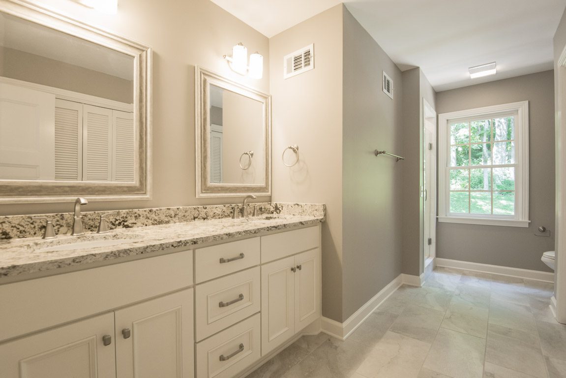 Bright bathroom with granite countertop and large mirror.