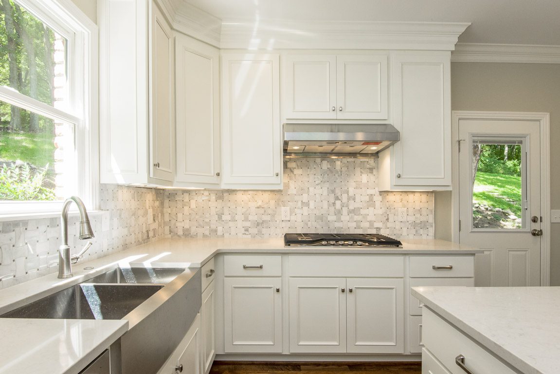 Bright kitchen with white cabinets and a tiled backsplash.