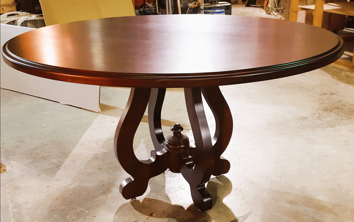 Elegant round wooden table with ornate pedestal base and claw feet.